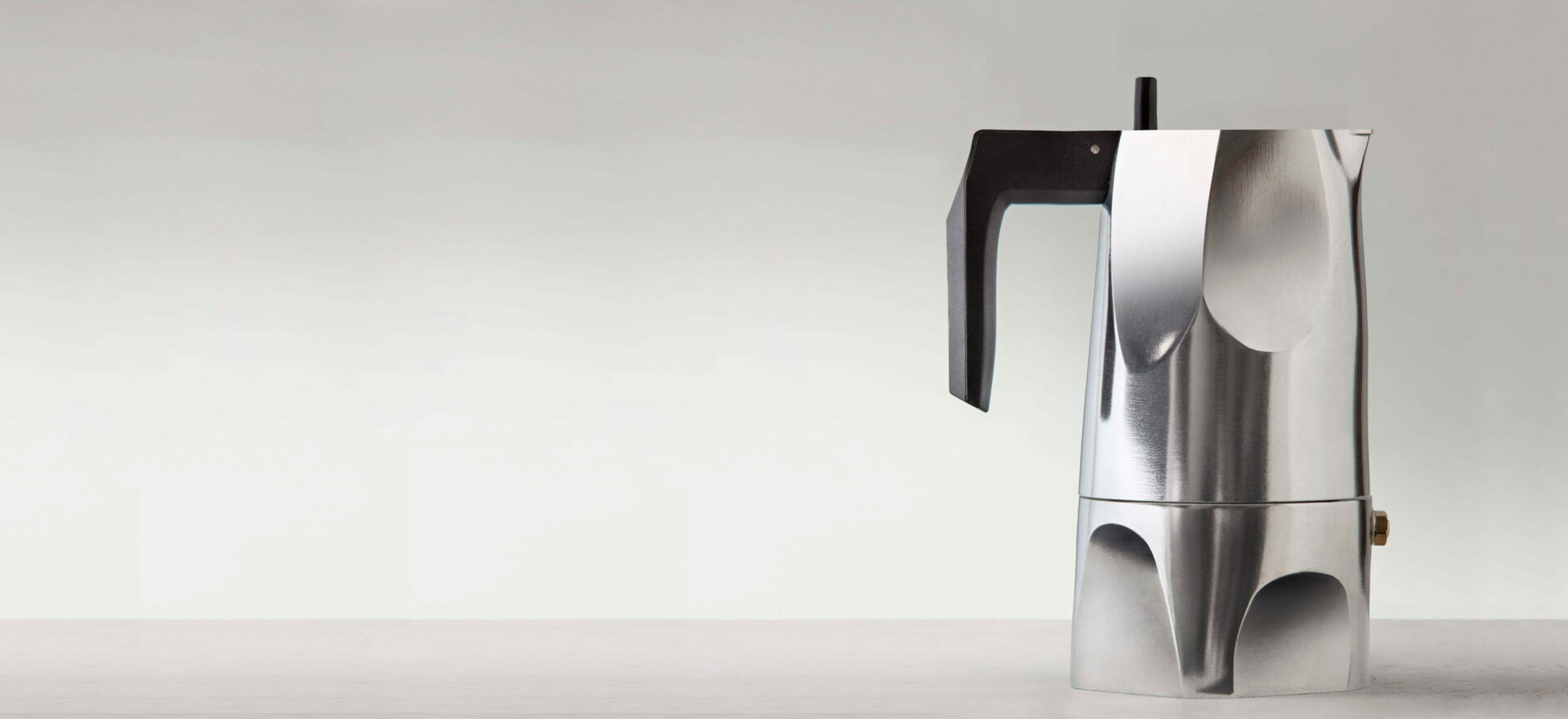 Right side photo of Ossidiana Expresso Coffee maker for Alessi. The model presented in the picture is in aluminium casting with handle in thermoplastic black resin, showing the details of its form inspired in the stone arrowheads handmade by natives.